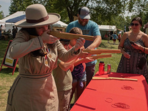 People lined up at a table and shooting toy guns'